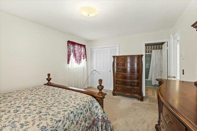 bedroom featuring a closet, ensuite bathroom, and light carpet