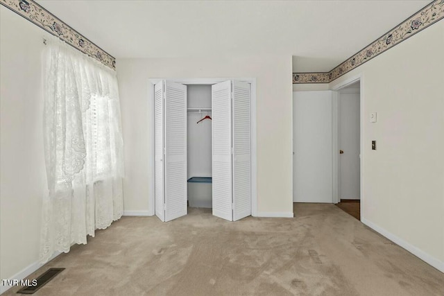 unfurnished bedroom with light carpet and a closet