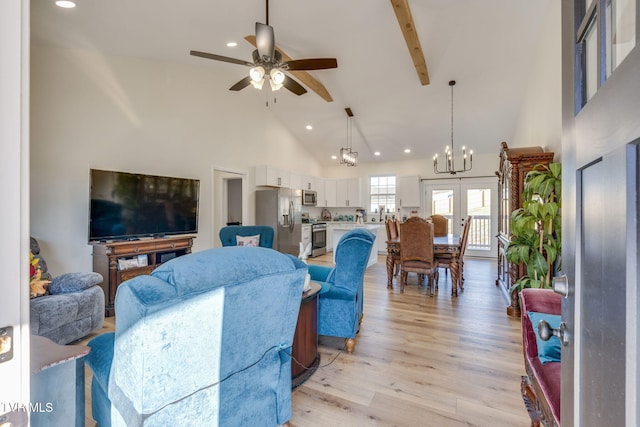 living room featuring high vaulted ceiling, ceiling fan with notable chandelier, french doors, and light wood-type flooring