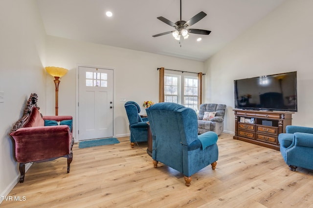 living room featuring ceiling fan, light hardwood / wood-style floors, and lofted ceiling