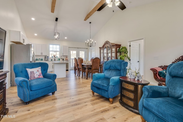 living room featuring light wood-type flooring, ceiling fan with notable chandelier, high vaulted ceiling, and beam ceiling