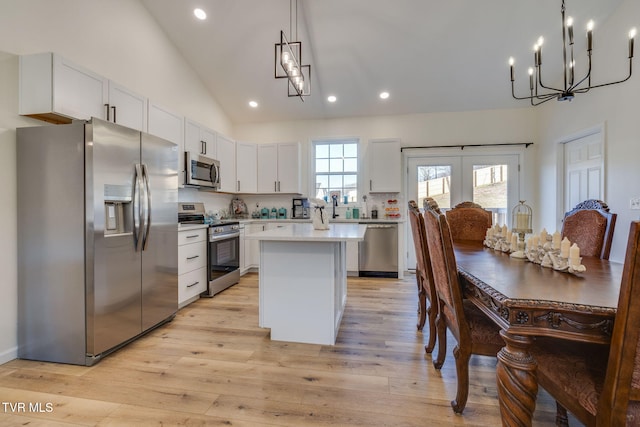 kitchen featuring a kitchen island, white cabinets, hanging light fixtures, and stainless steel appliances