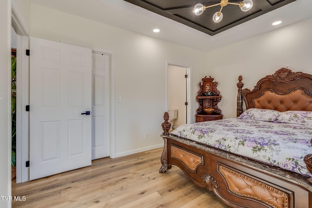 bedroom with a tray ceiling and light wood-type flooring