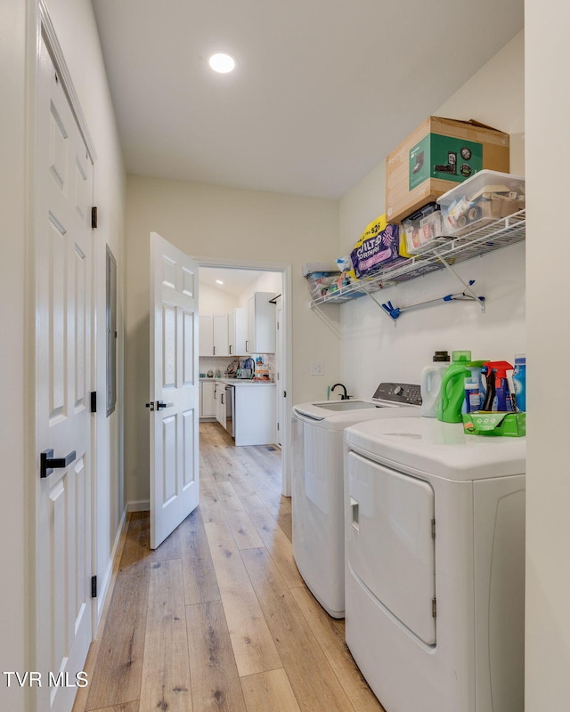 laundry area with light hardwood / wood-style flooring and washer and dryer