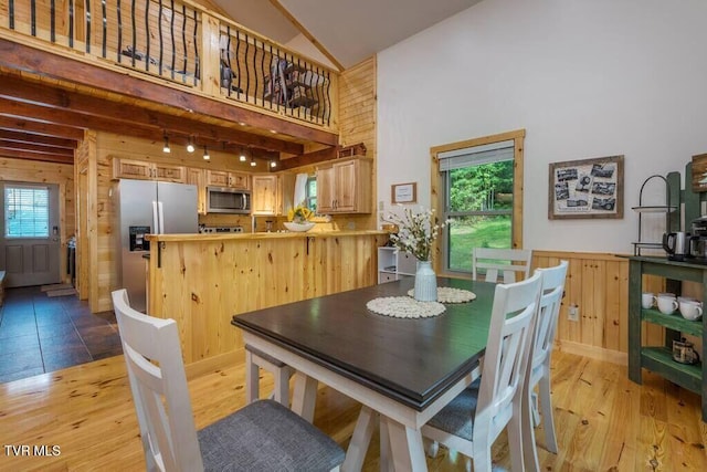 dining space featuring light hardwood / wood-style flooring, high vaulted ceiling, and a healthy amount of sunlight