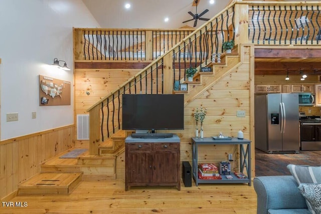 stairway featuring hardwood / wood-style flooring, ceiling fan, and wooden walls