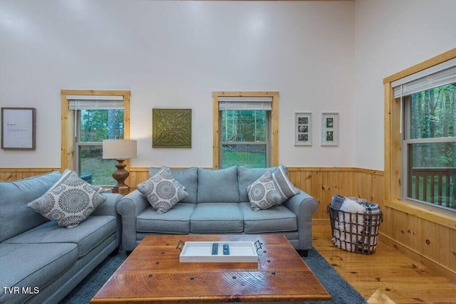 living room with a high ceiling, wood-type flooring, and wooden walls