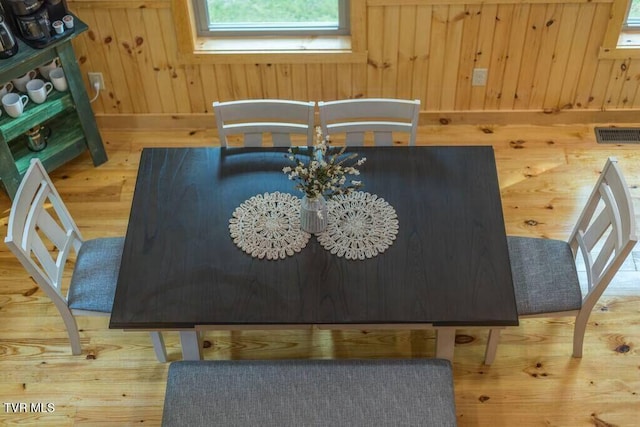 dining area featuring hardwood / wood-style floors and wood walls