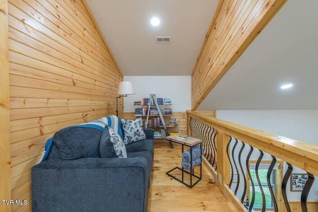 sitting room featuring vaulted ceiling, wooden walls, and light hardwood / wood-style floors