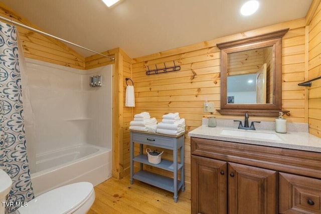 full bathroom with wood walls, shower / bath combination with curtain, hardwood / wood-style flooring, vanity, and toilet