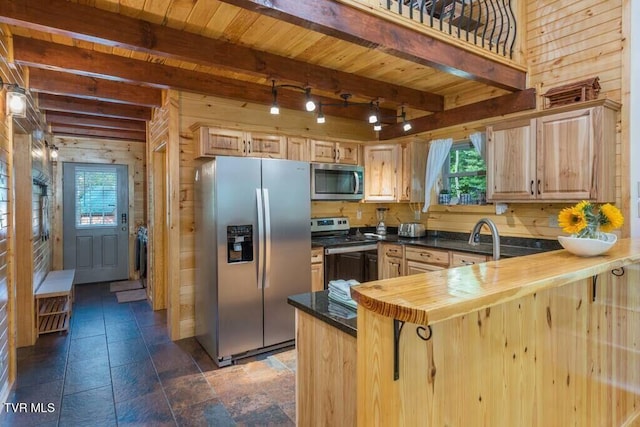 kitchen featuring stainless steel appliances, light brown cabinetry, butcher block countertops, and wood walls