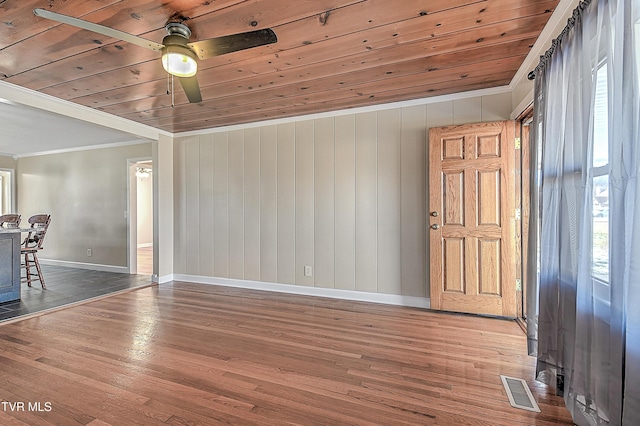 empty room with wood-type flooring, wooden ceiling, ceiling fan, and ornamental molding