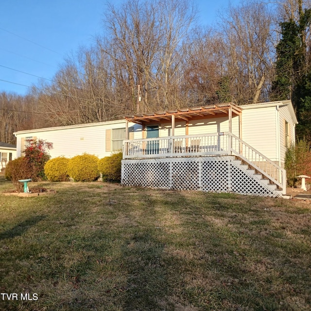 rear view of house featuring a wooden deck and a yard