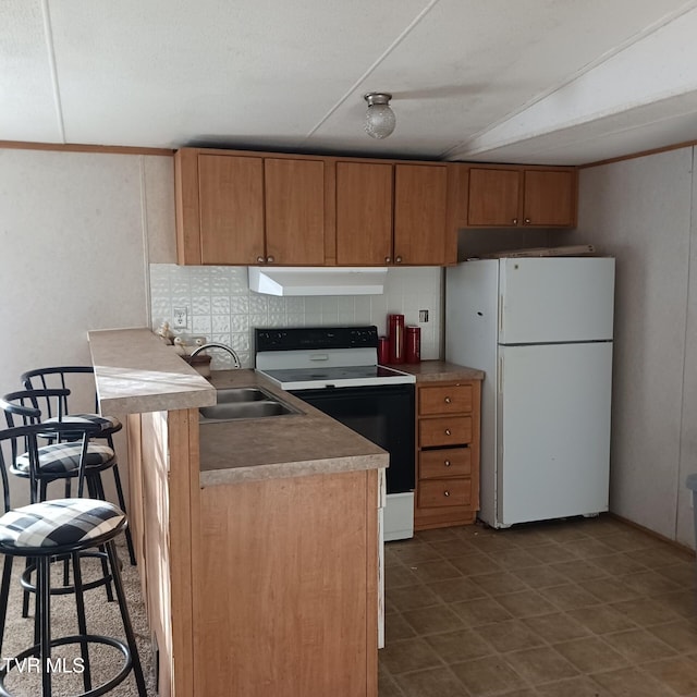 kitchen featuring a kitchen bar, sink, white refrigerator, electric stove, and decorative backsplash