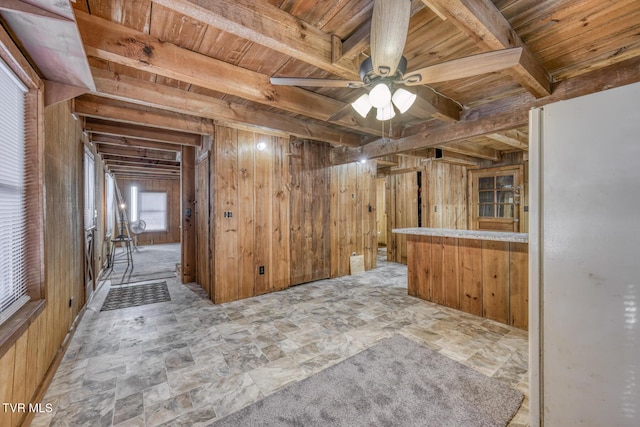 interior space featuring wood ceiling, ceiling fan, and wood walls