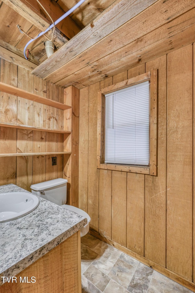 bathroom featuring sink, toilet, and wood walls