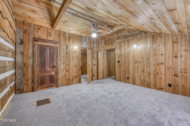 empty room featuring wood ceiling, carpet floors, and wood walls