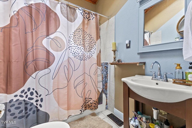 bathroom featuring visible vents, a textured wall, and tile patterned floors