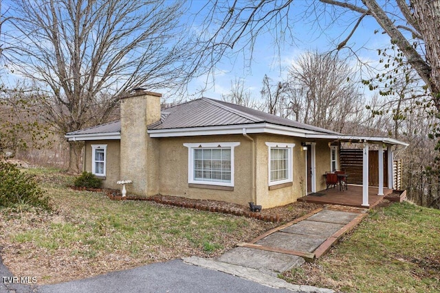 view of home's exterior featuring a yard, metal roof, a chimney, and stucco siding