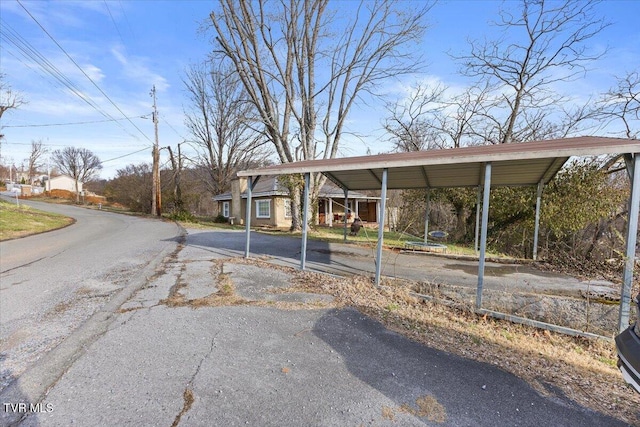 view of parking with aphalt driveway and a carport