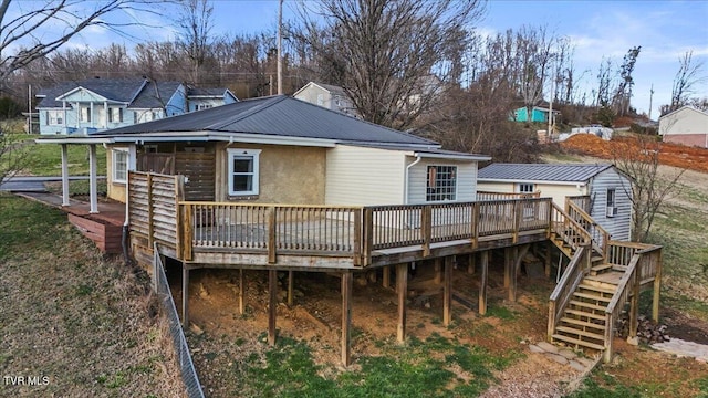 back of house featuring stairway, metal roof, and a wooden deck