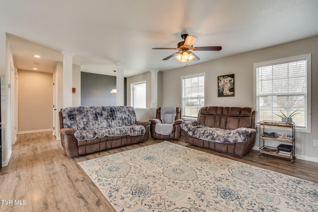 living room featuring hardwood / wood-style floors, ceiling fan, and ornate columns