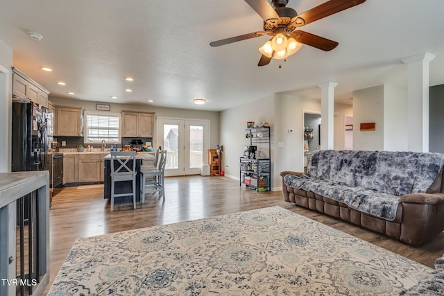 living room with ornate columns, sink, hardwood / wood-style floors, and ceiling fan