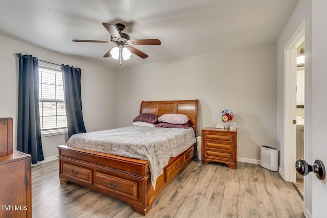 bedroom featuring light hardwood / wood-style floors, ceiling fan, and ensuite bathroom