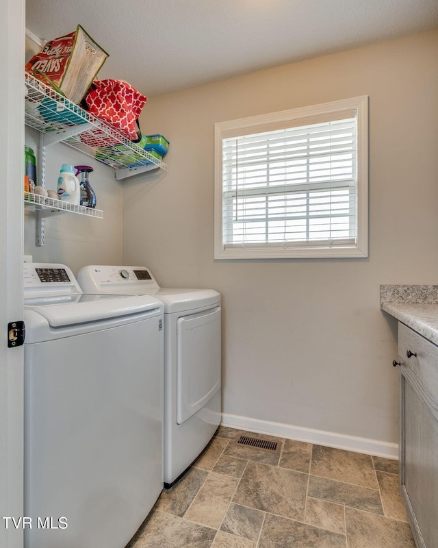 clothes washing area featuring separate washer and dryer and cabinets