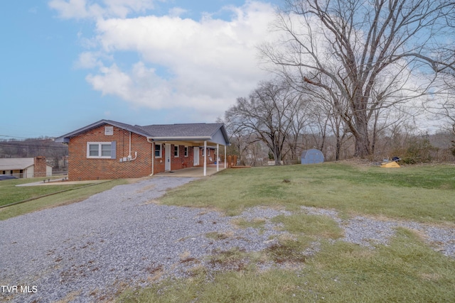 ranch-style home with a carport, a storage unit, and a front lawn