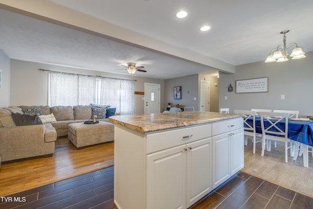 kitchen featuring white cabinetry, decorative light fixtures, a center island, and ceiling fan with notable chandelier