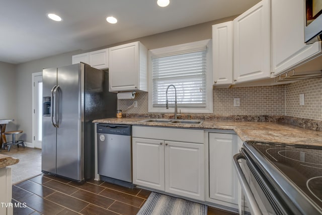 kitchen featuring stainless steel appliances, sink, dark stone counters, and white cabinets