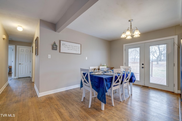 dining area with french doors, wood-type flooring, beam ceiling, and an inviting chandelier