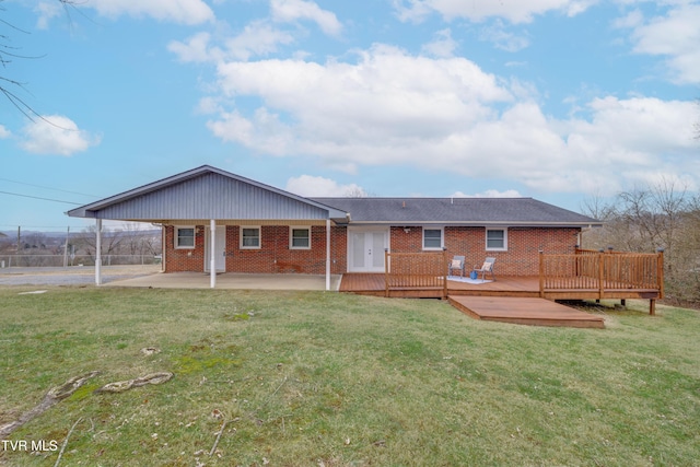 rear view of house with a wooden deck, a patio, and a lawn