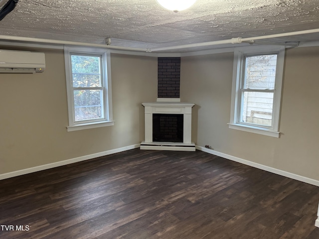 unfurnished living room with dark hardwood / wood-style floors, a wall mounted air conditioner, a textured ceiling, and a fireplace