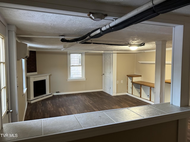 basement featuring dark hardwood / wood-style floors, a fireplace, an AC wall unit, and a textured ceiling