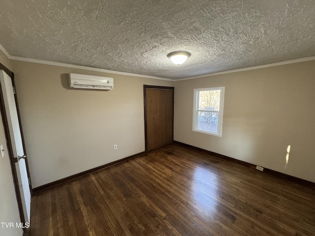 unfurnished bedroom featuring ornamental molding, a wall mounted AC, a textured ceiling, and dark hardwood / wood-style flooring