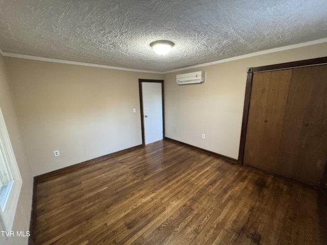 unfurnished bedroom with crown molding, an AC wall unit, dark wood-type flooring, and a textured ceiling