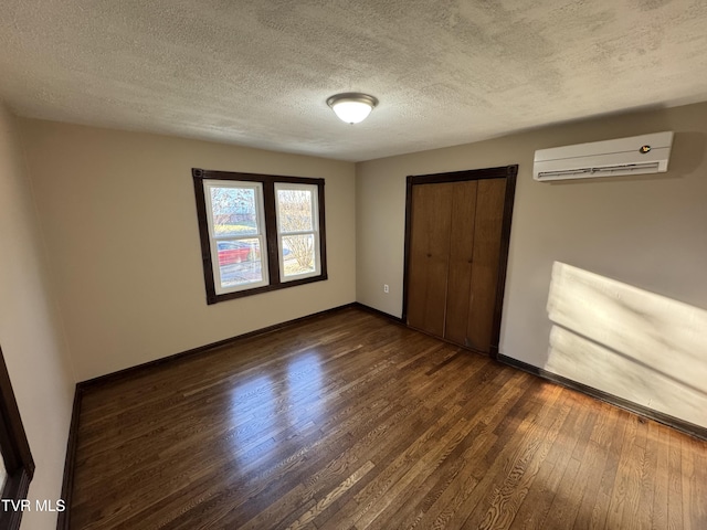 unfurnished bedroom featuring a wall mounted air conditioner, dark wood-type flooring, a closet, and a textured ceiling