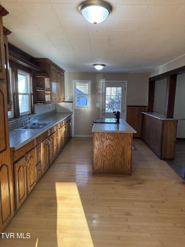 kitchen with light hardwood / wood-style floors, sink, a kitchen island, and a wealth of natural light