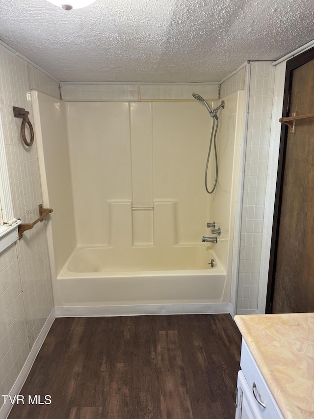 bathroom featuring vanity, hardwood / wood-style floors, a textured ceiling, and bathing tub / shower combination