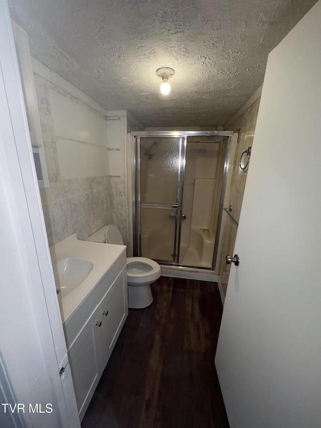 bathroom featuring hardwood / wood-style flooring, vanity, a textured ceiling, toilet, and walk in shower