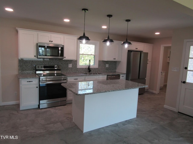 kitchen featuring a center island, a sink, appliances with stainless steel finishes, white cabinetry, and backsplash
