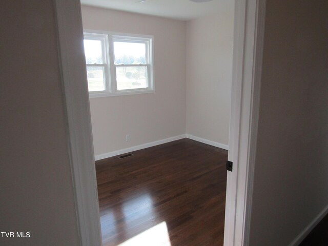 unfurnished room with dark wood-type flooring, baseboards, and visible vents