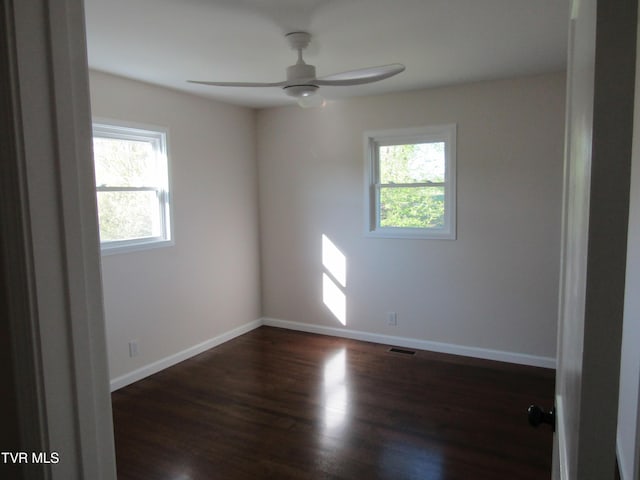 spare room featuring a ceiling fan, baseboards, dark wood-style floors, and visible vents