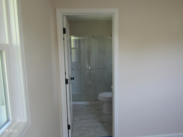bathroom with toilet, a stall shower, and marble finish floor