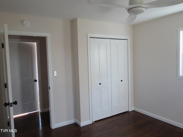 unfurnished bedroom featuring a closet, dark wood-style flooring, baseboards, and ceiling fan