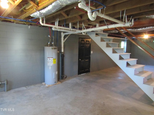 unfinished basement with water heater, stairway, and concrete block wall