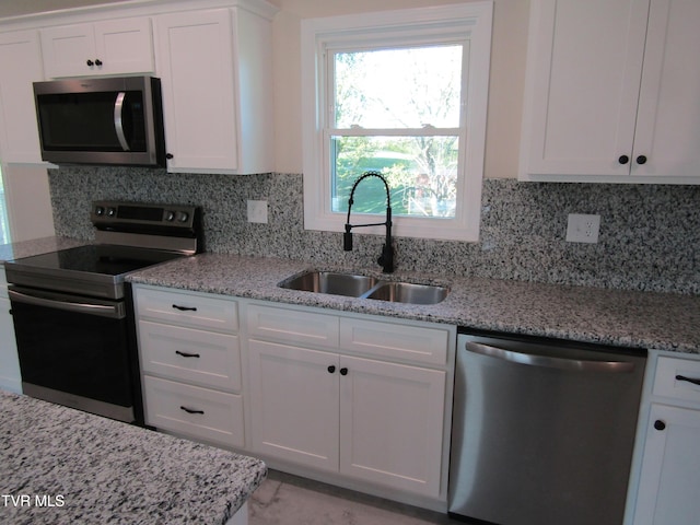 kitchen featuring stainless steel appliances, tasteful backsplash, white cabinets, and a sink