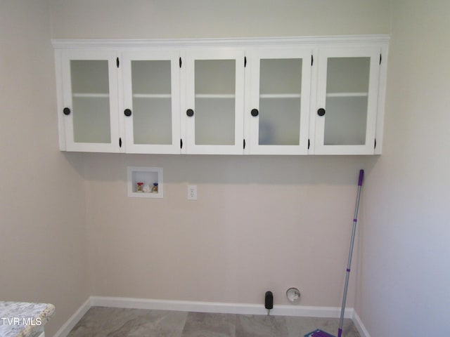 washroom with baseboards, washer hookup, and cabinet space